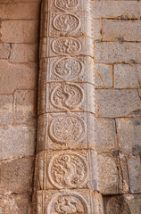 Hampi, Karnataka, India - November 5, 2013: Sri Krishna temple in ruins. Red stone sculpted frame of massive entry gate shows circled snake-like images, circled by long snake-like design.