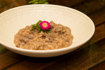 Risotto with chopped pork meat on wooden table in the background