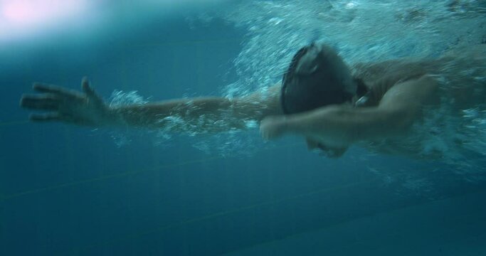 Adaptive amputee professional athlete butterfly swimming in indoor pool