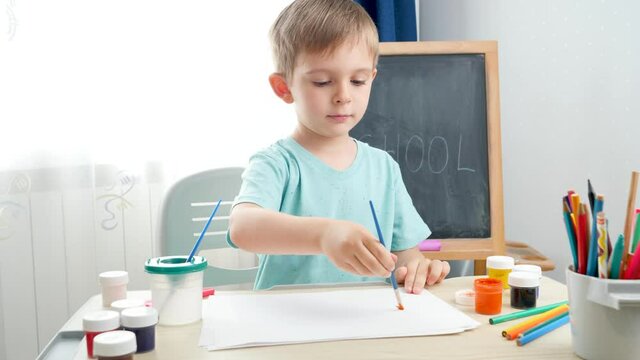 Little boy drawing picture with guache paint. Child education at home during self isolation and lockdown. Concept of art and creativity of children