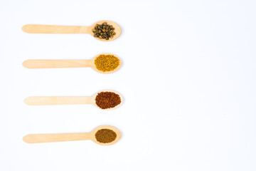 Various spice seeds in wooden spoons on a white background. Seeds of beet, mustard, lettuce, arugula, on a white background. Place for an inscription. View from above.