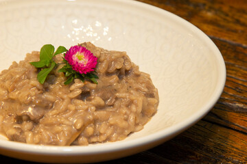 Risotto with chopped pork meat on wooden table in the background