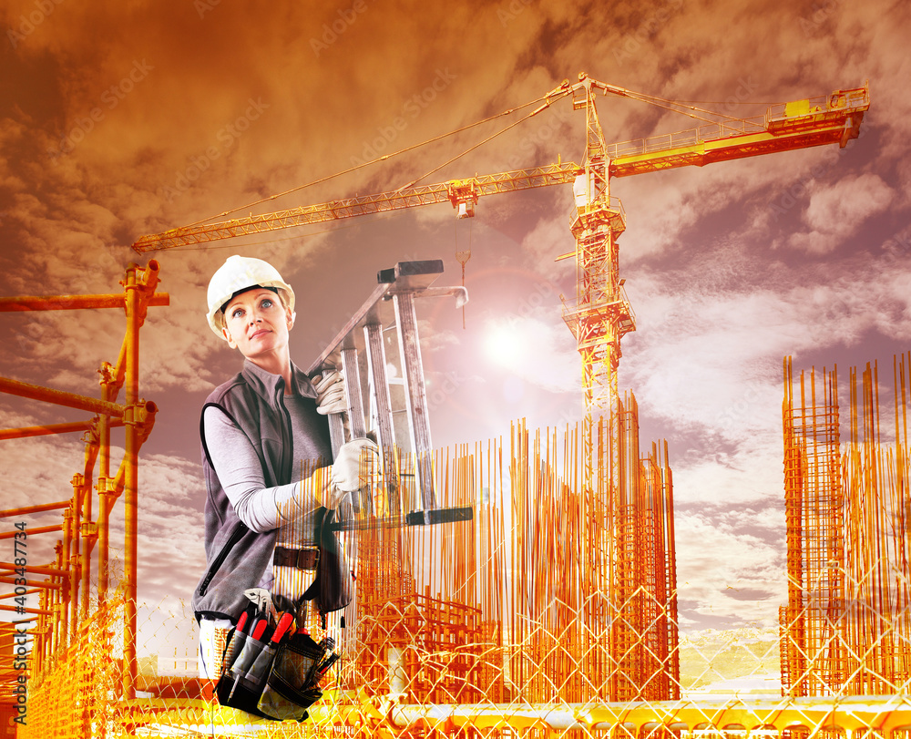 Wall mural woman construction worker on building site with crane with safety hard hat, tool bag and ladder, dou