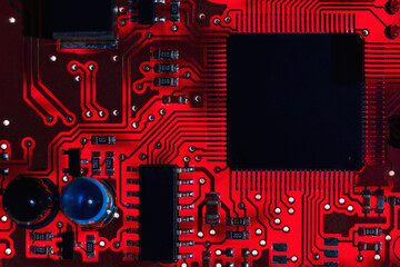 Close-up of a red printed circuit board (PCB) with stripes of conductors between a transistor and...