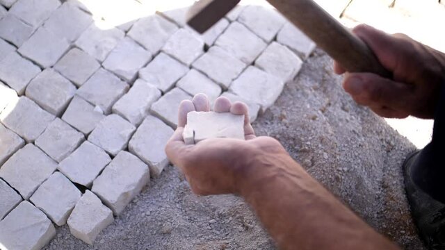 paver working on traditional portuguese cobblestone pavement slow motion