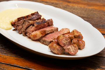 Barbecue with anchovy meat and sausage served with aligot.