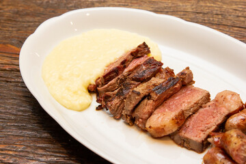 Barbecue with anchovy meat and sausage served with aligot.