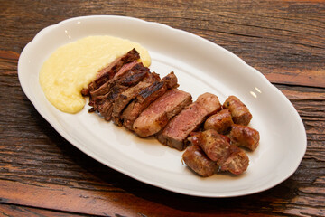 Barbecue with anchovy meat and sausage served with aligot.