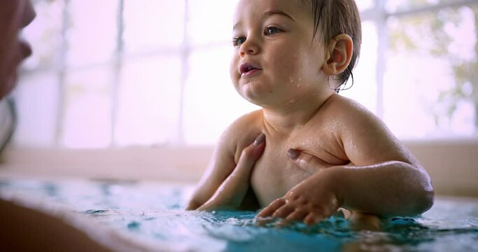Little baby learning to swim with mother in indoor pool