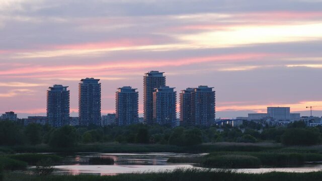 Timelapse of Vacaresti Park Nature Reserve in Bucharest, Romania, at sunset, with skyscrapers and Palace of Parliament, part of the city skyline. Nature, landmark, tourism, sightseeing, cityscape.