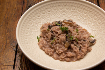 Mushroom risotto, on the wooden table.