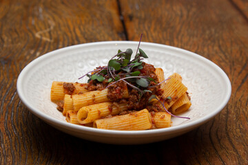 Rigatoni pasta with sugo sauce and lamb ragout, with coriander leaves on top.