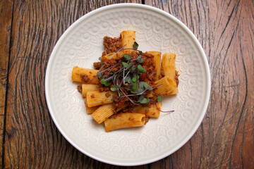 Rigatoni pasta with sugo sauce and lamb ragout, with coriander leaves on top.