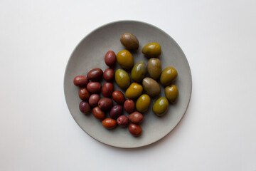 Green and purple olives on grey concrete plate isolated on white background from a high angle view