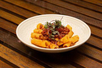 Rigatoni pasta with sugo sauce and lamb ragout, with coriander leaves on top.