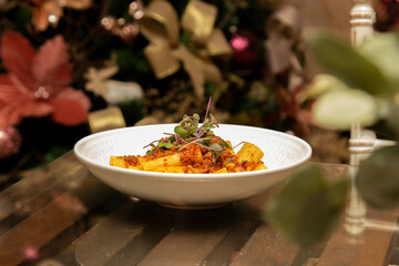 Rigatoni pasta with sugo sauce and lamb ragout, with coriander leaves on top. Christmas background.