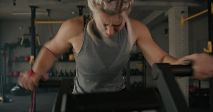 Sweaty female athlete exercising on stepping machine. Muscular sportswoman breathing heavily and exercising on stepping machine during intense fitness training in gym