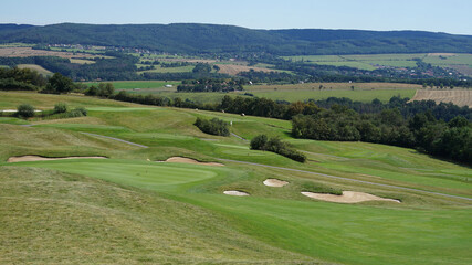 Fototapeta na wymiar Golf course with greens and sandy bunker hazards on the hill with panoramic view