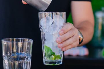 Close-up of male hands preparing a mojito cocktail.