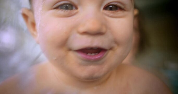 Happy baby smiling looking at camera playing in indoor pool