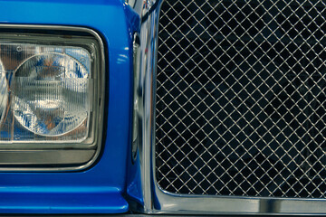 close-up of front halogen headlights of blue car in garage