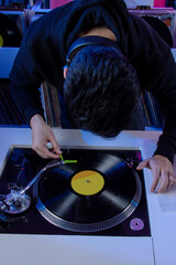 Dj colocando un disco de vinilo en su tocadiscos mientras mezcla música en una tienda de discos....