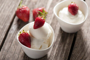 Fresh strawberries with homemade milk ice cream in bowl on the wooden table