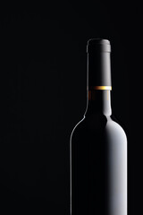 An unopened bottle of red wine on a black background.