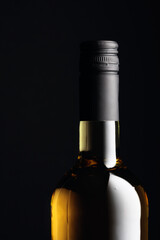 Unopened bottle of white wine on a black background.