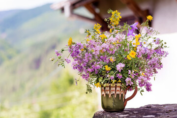 Beautiful Wild Spring Purple and Yellow Flowers  in a Small  Vintage Vase on a Summer Mountain Hills Background 