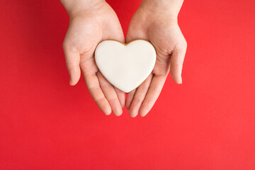Obraz premium Above top close up view photo of female hands showing holding homemade gingerbread cookies in shape of heart isolated bright background