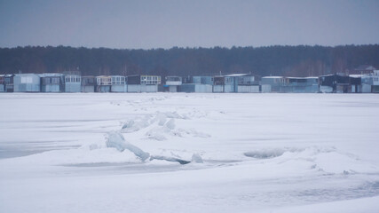 Houses of a fishing village on the banks of the frozen Voronezh reservoir in winter