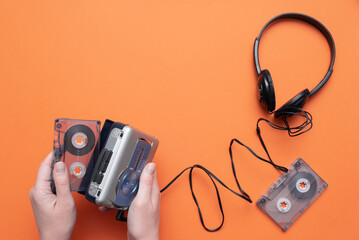 Old retro stereo cassette player and headphones on the orange flat lay background.