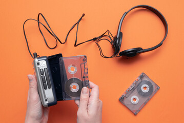 Old retro stereo cassette player and headphones on the orange flat lay background.