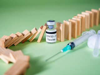 Domino effect stopped by covid-19 vaccine.Vial with covid-19 vaccine, syringe and dominoes on a...