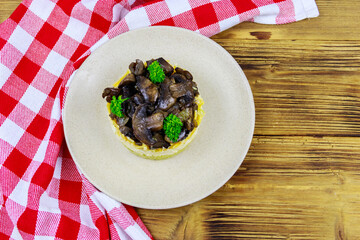 Tasty layered salad with roasted mushrooms, potato, eggs, cheese and mayonnaise on wooden table. Top view