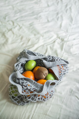 Gray mesh bag with yellow oranges close-up and copy space. Handmade eco bag on textiles