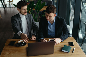 Two handsome businessmen are talking and pointing laptop screen while discussing. Business. Technology. Partnership.