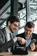 One-on-one meeting. Two young business people sitting at table in restaurant having a conversation using a phone and having a coffee