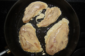 Chicken fillet in batter in a pan.