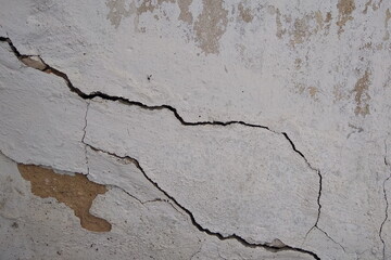 Grunge texture of an old concrete wall with peeling plaster and cracks. City view, old cracked wall.