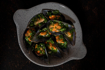 Some mussels and parsley in a small plate with handles.