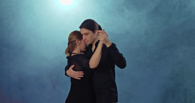 Beautiful couple is professionally dancing a passionate tango, the dancers are dancing in pairs. Loving couple dances romantically in a hall with smoke. 4k, ProRes