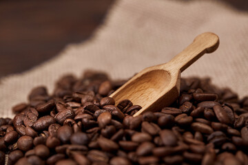 Coffee beans on burlap sack with wooden scoop