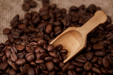 Obraz premium Dark roasted coffee beans with a scoop on a woven background