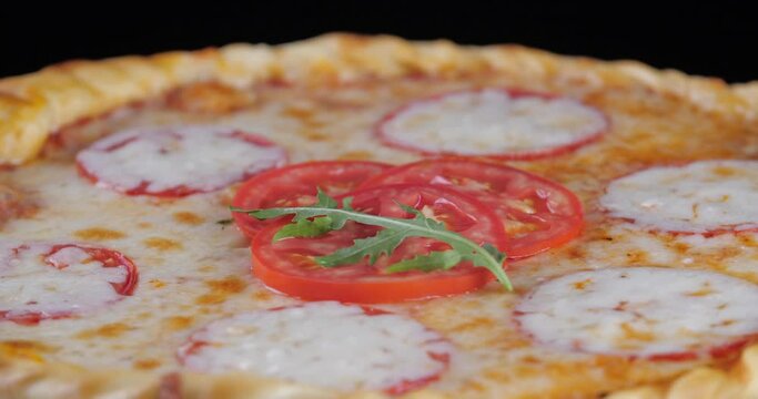 Close-up of delicious appetizing pizza margarita paperoni according to chef's signature recipe italian food spinning on board baked goods with tomatoes cheese and spices basil seasoning leaf falling