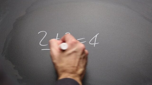 Hand writing “2+2=4” on chalkboard and highlighting. Concept of math and basic simple solution