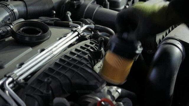Oil filter change car engine service mechanic gloved hands closeup