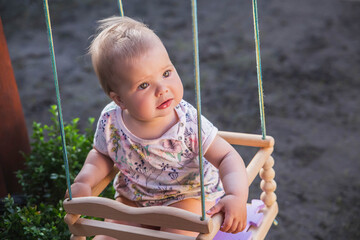 cute beautiful baby swinging in the yard on a swing sticking 