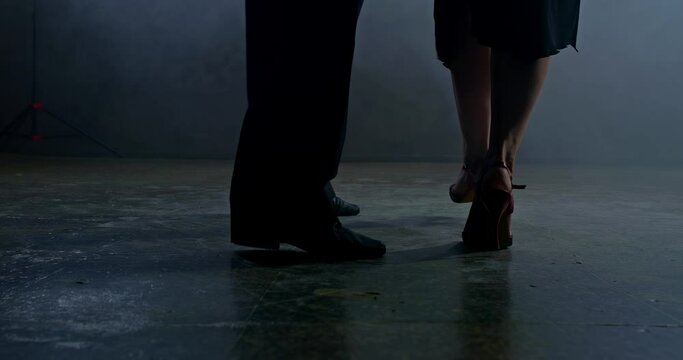 Close-up, legs of a man and a woman dancing latin dances in a dark room with smoke. Legs of a woman and a man dance beautifully on the dark floor. 4k, ProRes